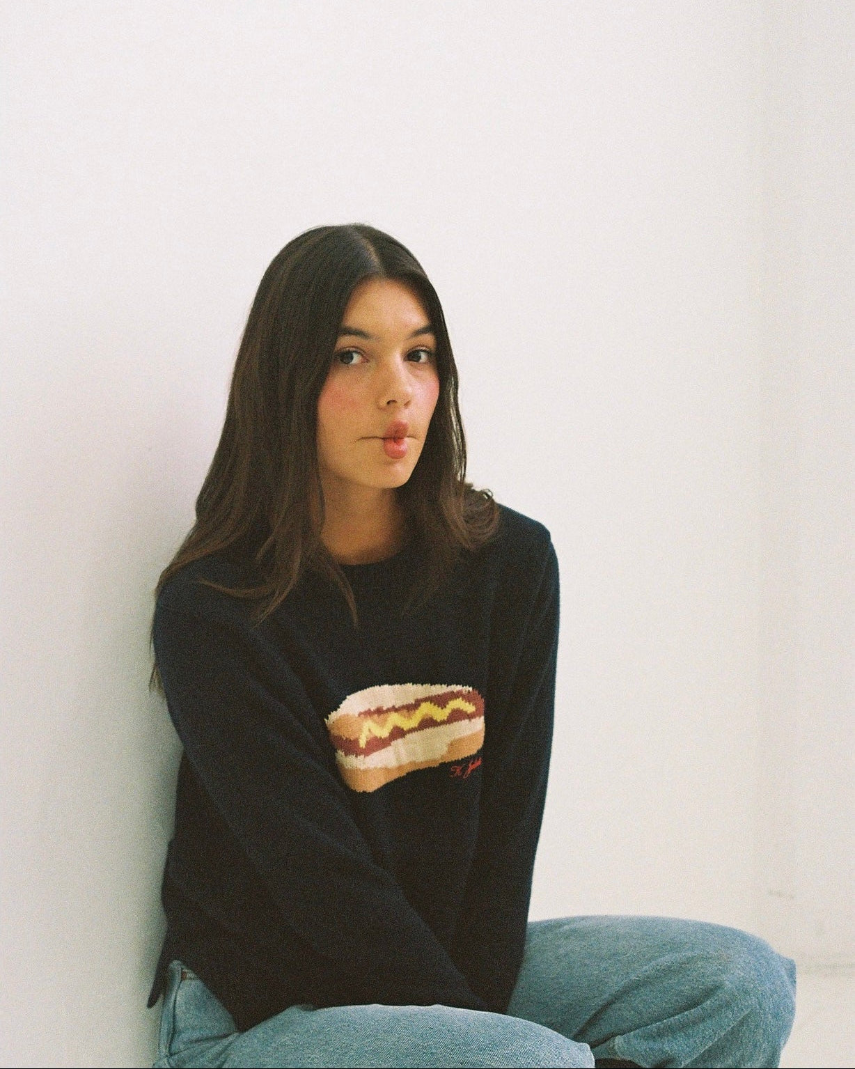 Person wearing a black sweater with a hot dog graphic against a white background