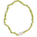 A beaded necklace made of small lime green chips with a single white baroque pearl accent, displayed on a clean white background.