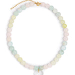 A pastel beaded necklace with round stones in soft pink, mint green, and pale yellow, accented by a gold-tone clasp and extender chain, with a clear heart-shaped pendant at the center, shown on a plain white background.
